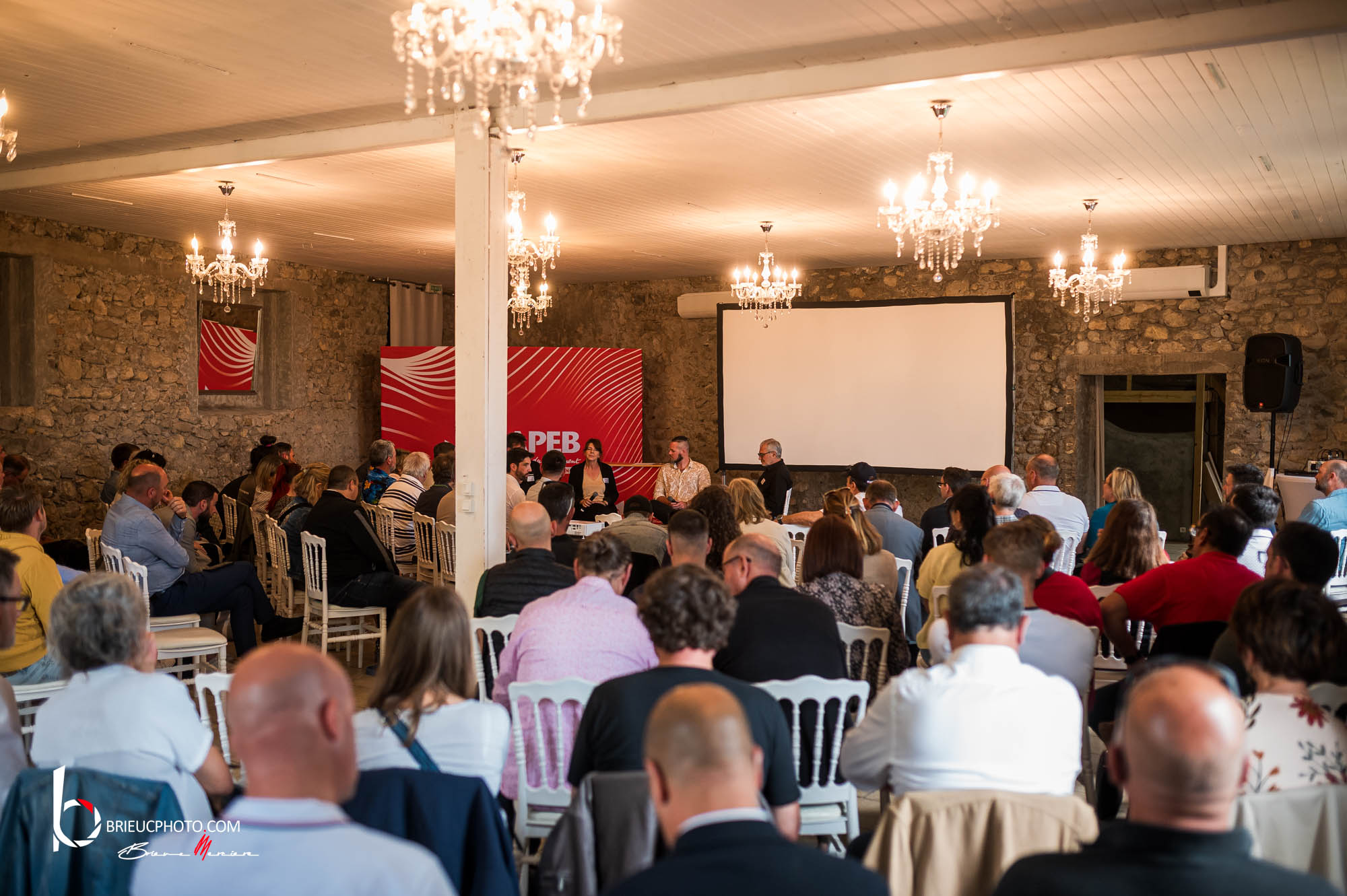 Conférence CAPEB devant une salle d'artisans du bâtiment, débat sur l'usage de l'IA dans le métier